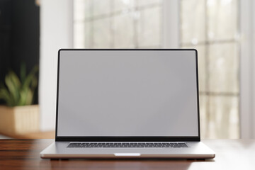 Fototapeta premium Laptop computer with blank white screen on wooden table_