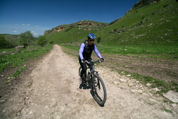A young woman on a bicycle in the Caucasus mountains, Russia.