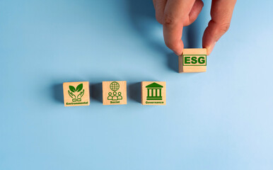 Hand holds wooden cubes with abbreviation ESG. ESG concept of environmental, social and governance....