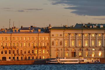 Residential buildings on the river embankment of a European city in the light of the setting sun. Evening urban landscape of the old city.