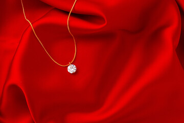 Golden necklace with pendant on red silk background - obrazy, fototapety, plakaty