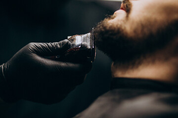 Handsome man cutting beard at a barber shop salon