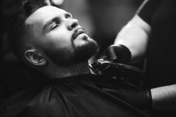 Handsome man cutting beard at a barber shop salon