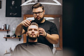 Hairdresser at a barber shop styling hair of a client