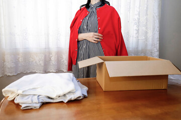 ネットショップでお買い物　届いた洋服を開封して着てみる女性