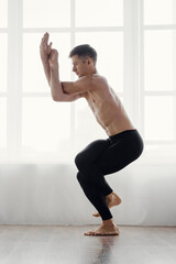 Strong male athlete standing in yoga position and stretching, Yoga stretch: male athlete showcases strength in pose.