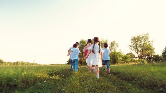 Cute little girl with family run fast in meadow grasses on summer vacation