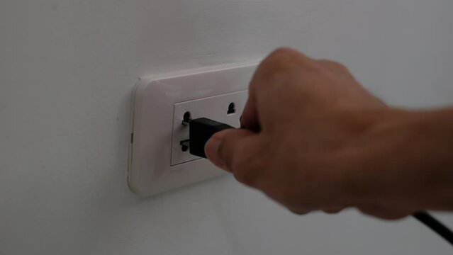 closeup plugging in wall outlet 