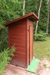 Fototapeta na wymiar Forest hut or wooden toilet with a heart-shaped ornament in the middle of the forest