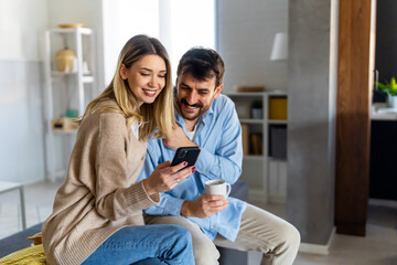 Smiling couple embracing while looking at smartphone. People sharing social media on smart phone.