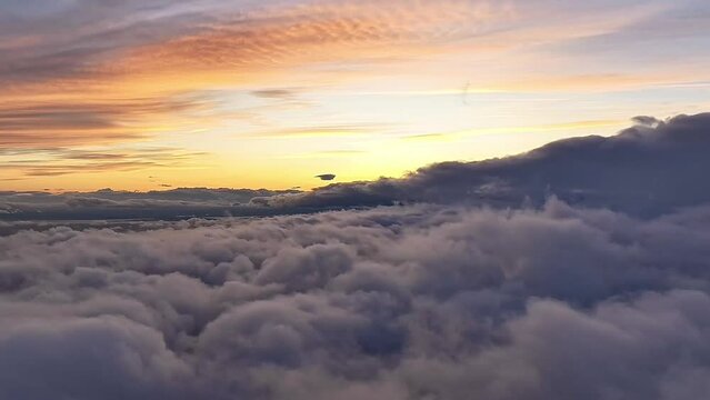 Time-lapse aerial footage over the dense clouds with colorful dusk sky in the background