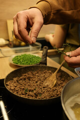 cooking minced meat on the stovetop in a skillet in the kitchen