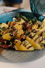 Fresh salad with oranges, avocados, tomatoes, greens with sauce in a blue plate