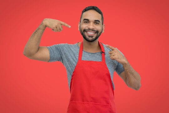Motivated hispanic waiter with apron on red background