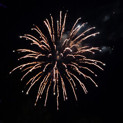Photo of real fireworks with smoke and golden sparks on black sky background for overlay blending mode.