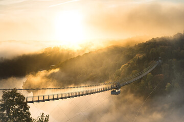 Titel: Blick auf die Hängebrücke Titan RT im Harz zum Sonnenaufgang. Nebelfelder über den Bäumen und im Bodetal. - obrazy, fototapety, plakaty