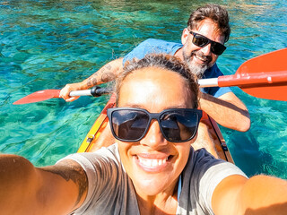 Happy active adult couple enjoying kayak canoe excursion trip tour on transparent blue clean water at the sea. Concept of happiness man and woman in summer holiday vacation. Healthy lifestyle. Tourist