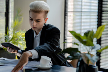 Concept of finance analytics. Serious businesswoman doing reports review. Female executive director with blonde short hair watching papers and holding tablet