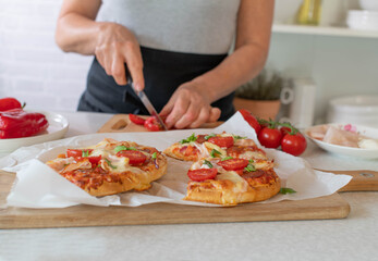 Pimped up baked frozen  pizza is prepared by a woman in the kitchen