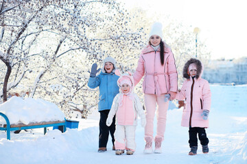 Family with children play snowy winter games in the park. Winter holidays and family vacation. Winter walk on the street on a sunny frosty day.