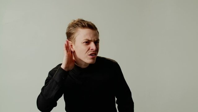 A guy misunderstands interlocutor due to poor hearing or pretends deaf for showing ignoring and mocking the unpleasant interlocutor. A young man cannot hear the speaker because of loud music or noise
