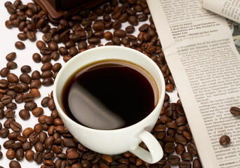 Black coffee and coffee beans on newspaper