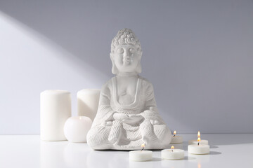 Buddha statue and candles on white background