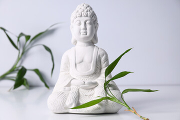 Buddha statue and leaves on white background