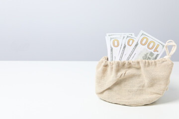 A bundle of 100 bucks in a bag on a light background.