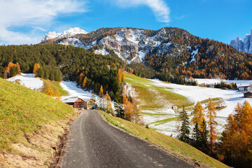 Fototapeta na wymiar Countryside rural landscape with а country road on a sunny day in late autumn, Val di Funes, Dolomite mountains, South Tyrol, Northern Italy.