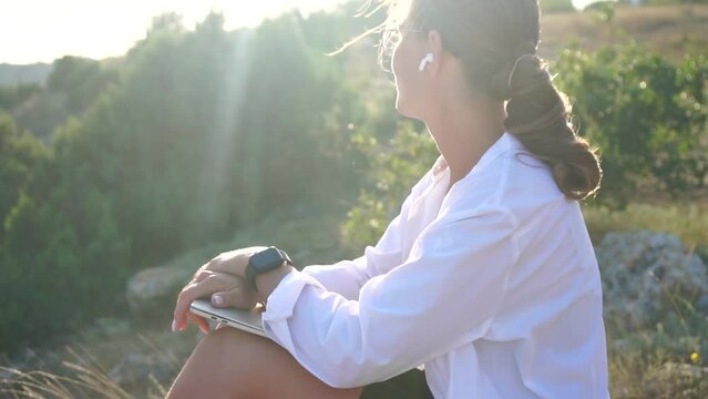 Woman laptop park. Working remotely on seashore. Happy successful woman female freelancer working on laptop at summer sunset, makes a business transaction online. Freelance, remote work on vacation