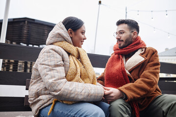 Fototapeta premium Portrait of young couple holding hands in winter outdoors and looking at each other smiling