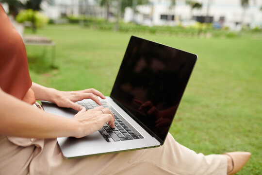 Closeup image of businesswoman working on laptop in city park