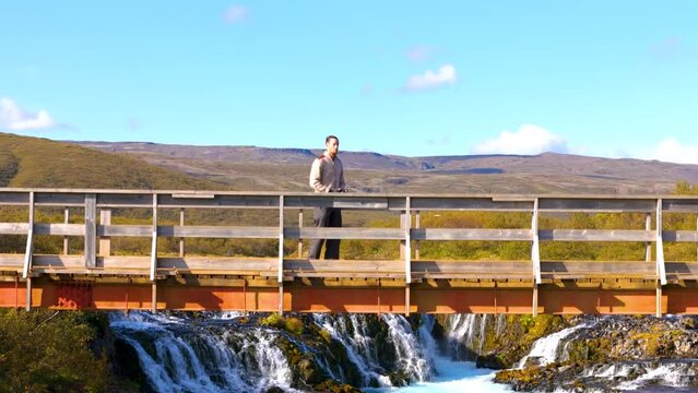 Aerial view, Man standing on lookout bridge for the scenic waterfall in Gullfos, Iceland.
