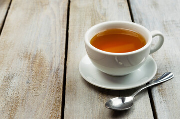 A cup of fragrant hot tea on a light background. Herb tea. Hot drink. White cup with tea.
