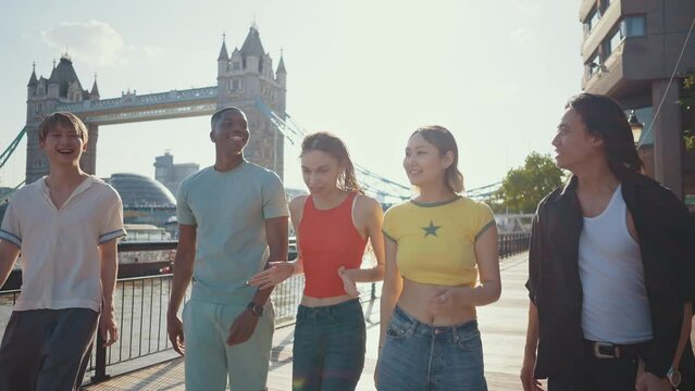 Group of teenagers friends spending time in the main areas of London as the tower bridge. Concept about generation z and friendship