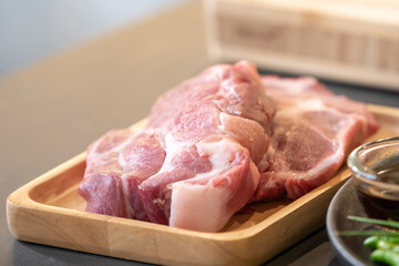 Raw Pork is prepared for Cook, It is on wood plate on black granite kitchen counter tabletop, shot by studio light.
