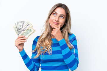 Young Uruguayan woman taking a lot of money isolated on white background looking up while smiling