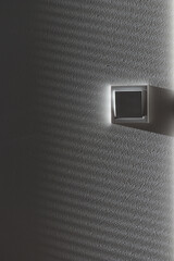 Light switcher on the white wall beneath rays of light