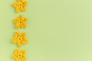 Yellow crocheted flowers row pattern on a green background.