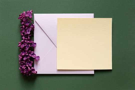 Happy birthday, Valentine's day, Easter, mother's day, wedding composition. Blank greeting card, invitation and envelope mockup. Square blank with delicate lilac flowers. Flat lay, top view.