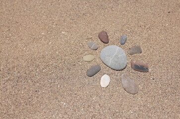 Close-up of stones put in form of sun, sandstone on sandy beach, hot sand, holiday time. Summer, coastline, nature, vacation, shore concept. Copy space