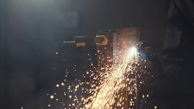 A man works with a circular saw. Sparks fly from hot metal. The man worked hard on the steel. Time-lapse close-up of a garage.