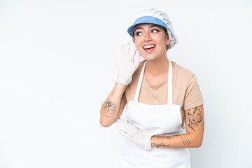 Fishmonger wearing an apron and holding a raw fish isolated on white background listening to something by putting hand on the ear
