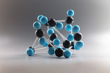 Close-up of molecular model structure, miniature on grey background, blue and black cells connected...