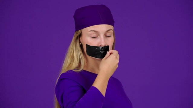 Young woman removing tape from mouth. Silence and taboo concept
