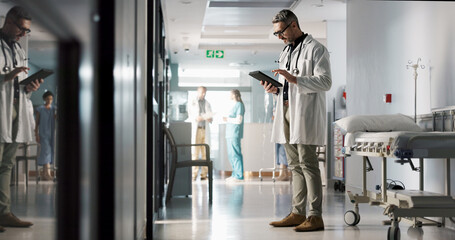 Doctor, man and tablet with reading, corridor and planning for surgery, advice or check in hospital. Medic, touchscreen and typing with contact, app or brainstorming for medical innovation in clinic
