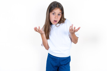 Frustrated Beautiful little kid girl wearing white T-shirt  feels puzzled and hesitant, shrugs...