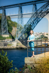 A woman in a blue dress stands on a city promenade. Porto, Portugal.