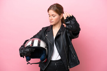 Young caucasian woman with a motorcycle helmet isolated on pink background making stop gesture and disappointed